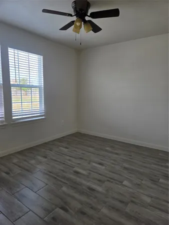 an empty room with wooden floor chandelier fan and windows