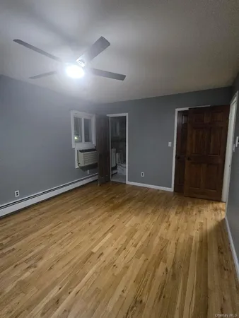 a view of empty room with wooden floor and window