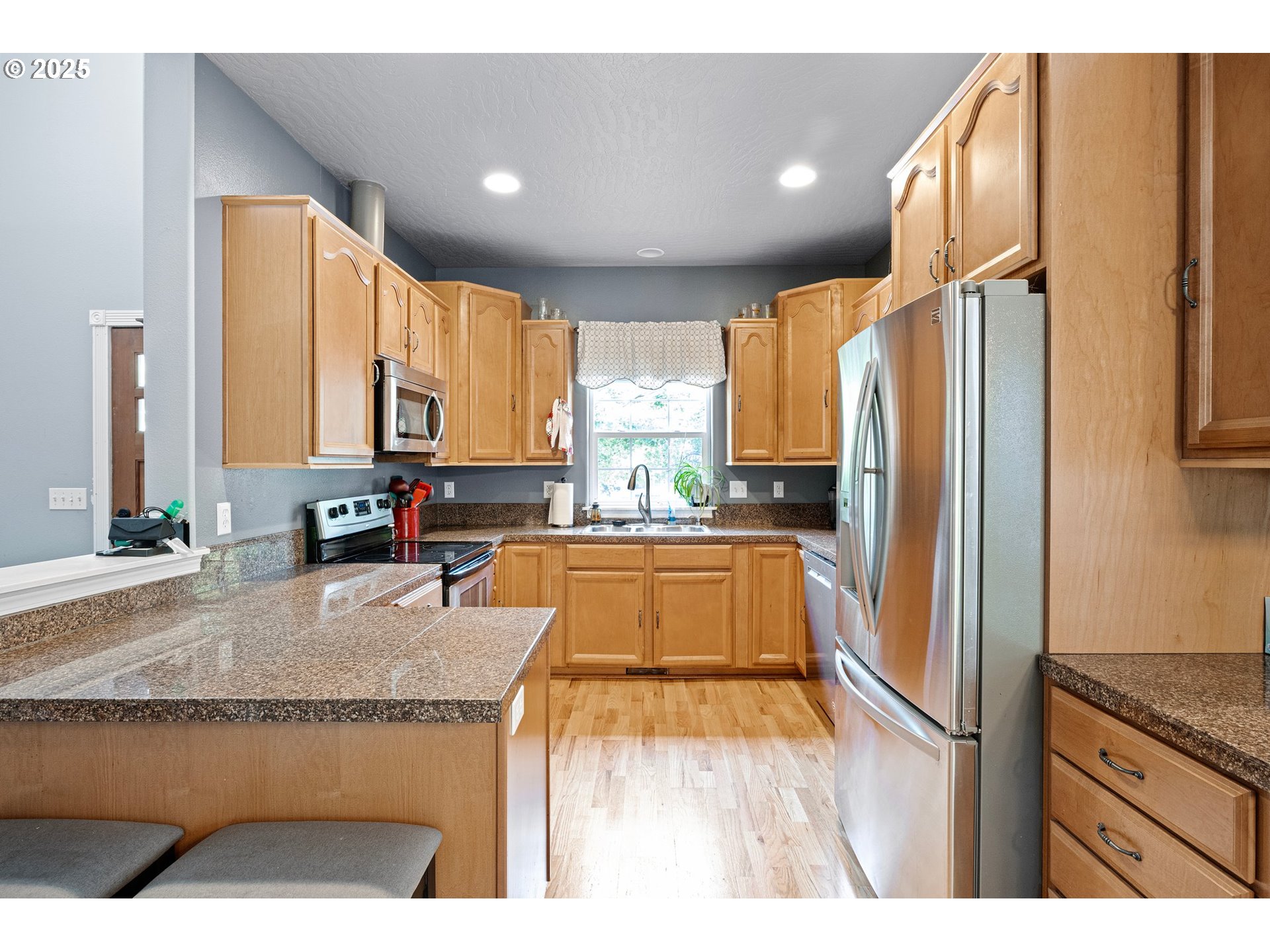 952 South 69th Street Springfield, OR 97478 - Photo 7 of 25 a kitchen with stainless steel appliances granite countertop a refrigerator a stove and a sink with wooden floor
