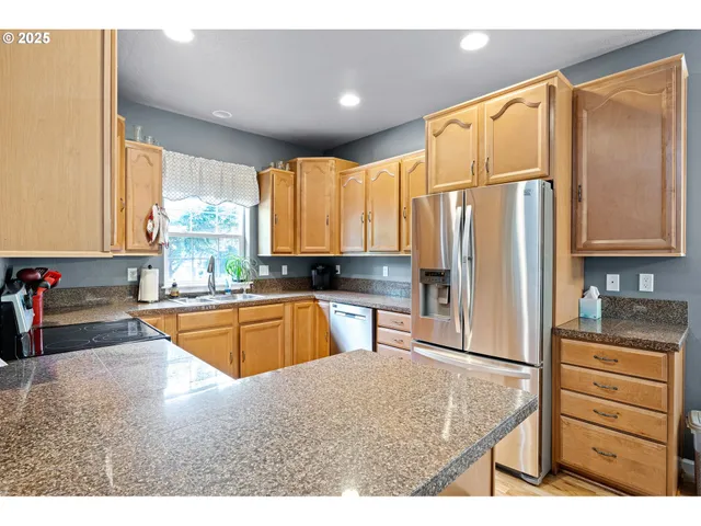 a kitchen with stainless steel appliances granite countertop a refrigerator a sink and a stove