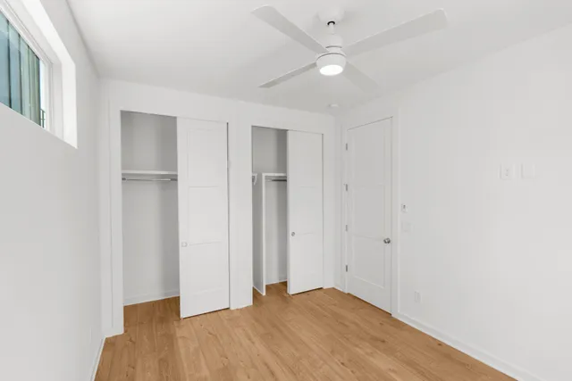 an empty room with windows and fan