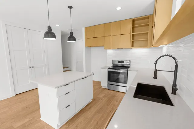 a kitchen with stainless steel appliances granite countertop a sink a stove and a wooden floors