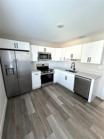 a kitchen with stainless steel appliances a stove a sink dishwasher a refrigerator and a microwave oven with wooden floor