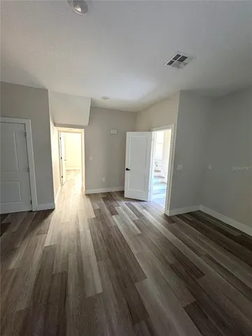 a view of an empty room with wooden floor and window