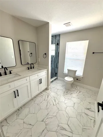 an empty room with wooden floor ceiling fan and windows