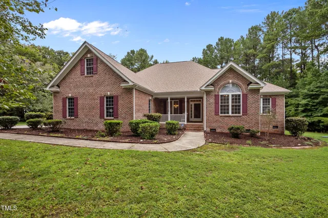 a front view of a house with a yard and trees