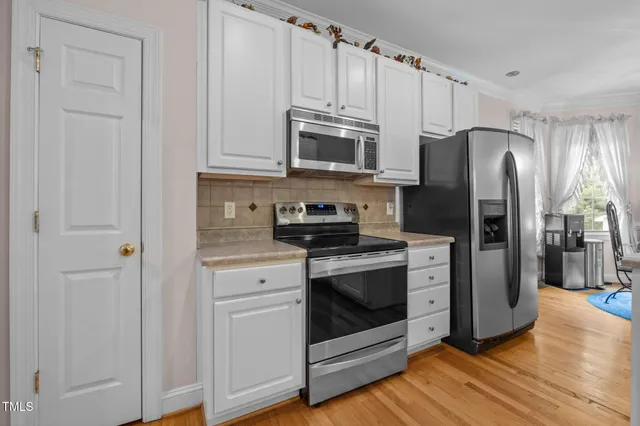 a kitchen with stainless steel appliances granite countertop a refrigerator stove and white cabinets