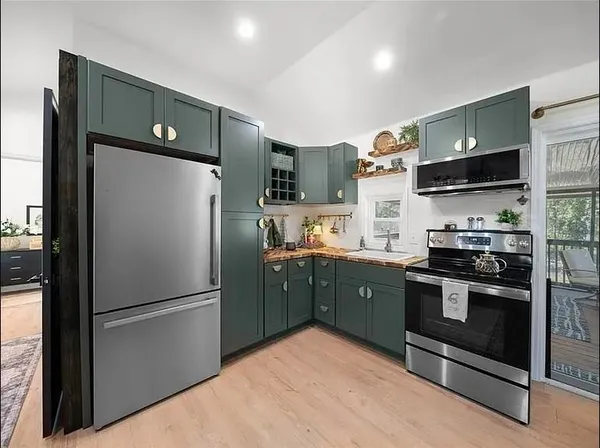 a kitchen with stainless steel appliances granite countertop a refrigerator a stove and a sink