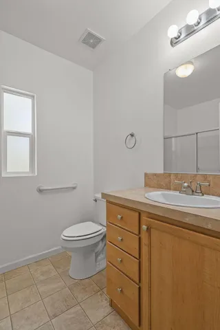 a bathroom with a granite countertop toilet a sink and a mirror