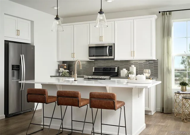a kitchen with stainless steel appliances a stove a sink refrigerator and white cabinets