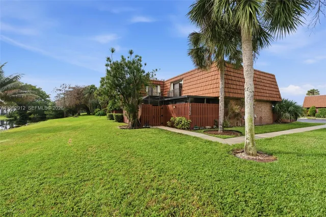 a backyard of a house with plants and palm tree