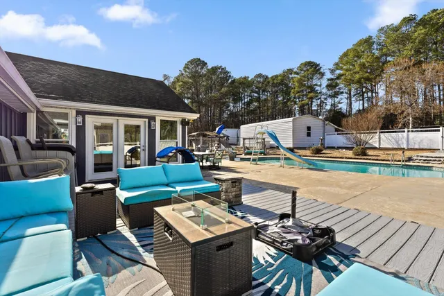 a view of a patio with couches table and chairs with wooden floor and fence