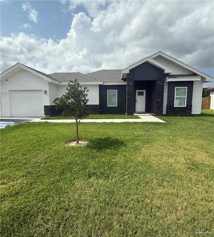 202 La Homa Road Mission, TX 78572 - Photo 1 of 1 Ranch-style house featuring a front lawn, stone siding, an attached garage, and a shingled roof