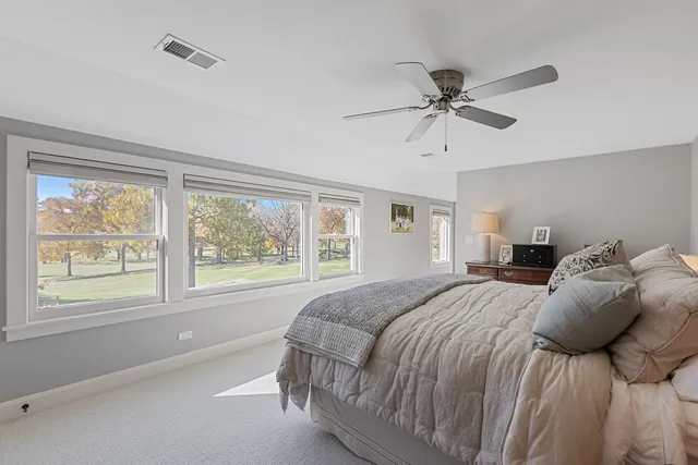 a bedroom with a large bed and a chandelier fan