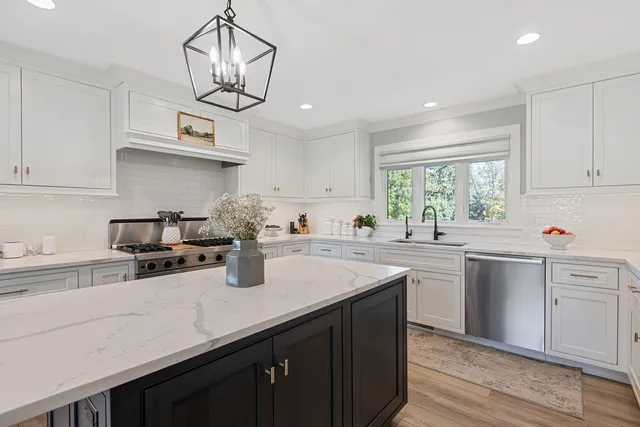 a kitchen with stainless steel appliances a sink a stove a center island and cabinets