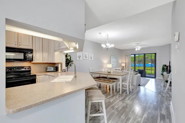 a kitchen with stainless steel appliances granite countertop a stove top oven a sink a dining table and chairs with wooden floor