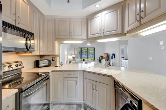 a kitchen with stainless steel appliances granite countertop a sink a stove top oven a chimney and cabinets