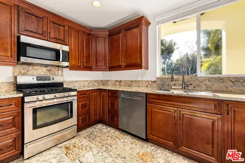 a kitchen with stainless steel appliances granite countertop a stove a sink and a microwave