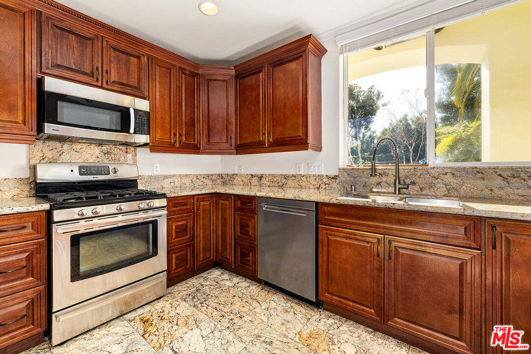 632 North Kings Road, Unit 101 West Hollywood, CA 90048 - Photo 2 of 14 a kitchen with stainless steel appliances granite countertop a stove a sink and a microwave