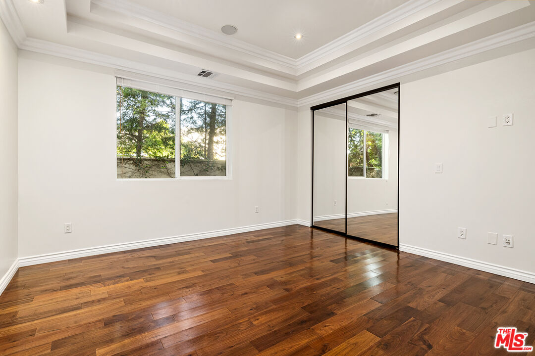 632 North Kings Road, Unit 101 West Hollywood, CA 90048 - Photo 5 of 14 an empty room with wooden floor and windows