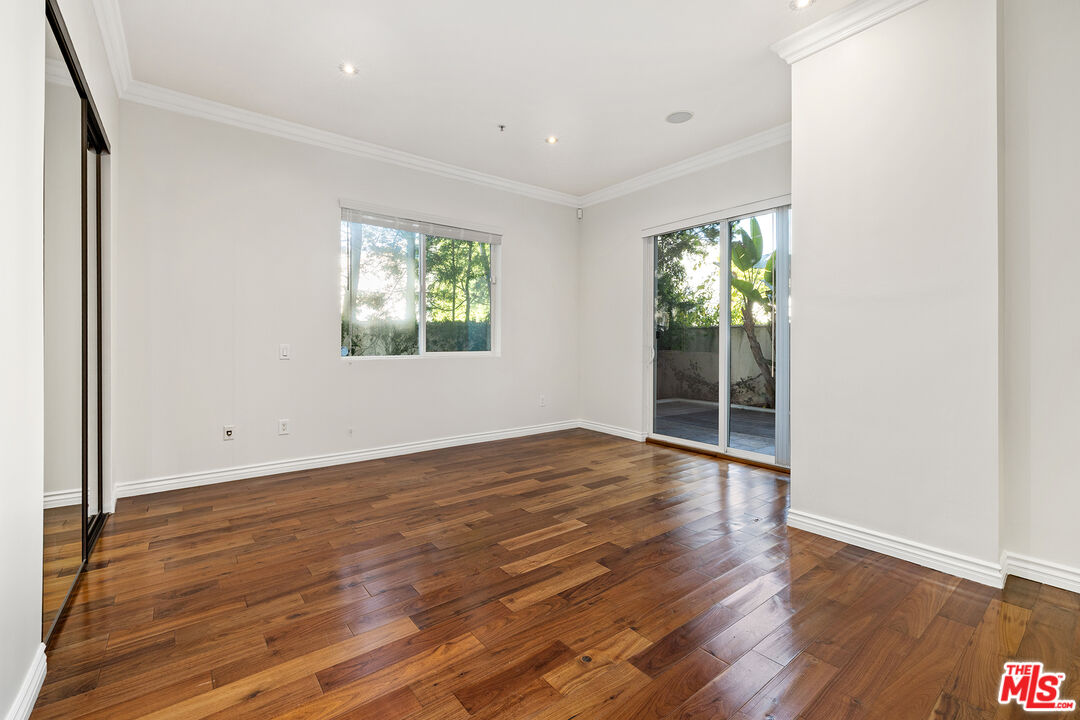 632 North Kings Road, Unit 101 West Hollywood, CA 90048 - Photo 7 of 14 an empty room with wooden floor and windows