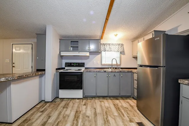 a kitchen with granite countertop a refrigerator stove and sink