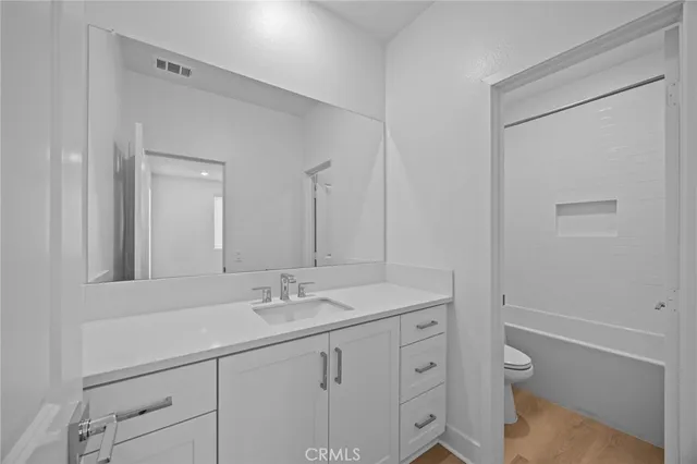 a bathroom with a granite countertop sink a toilet and a shower