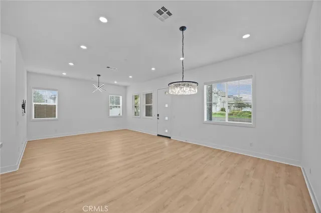 a view of an empty room with window and chandelier fan