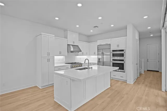 a kitchen with stainless steel appliances a stove a sink and a refrigerator