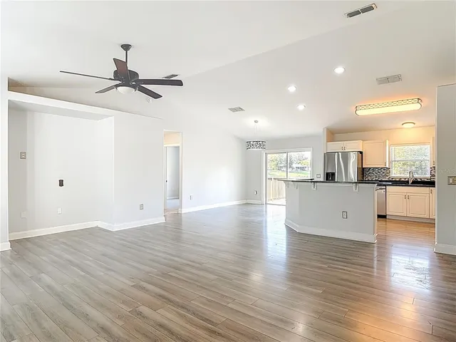 a view of empty room with wooden floor and ceiling fan