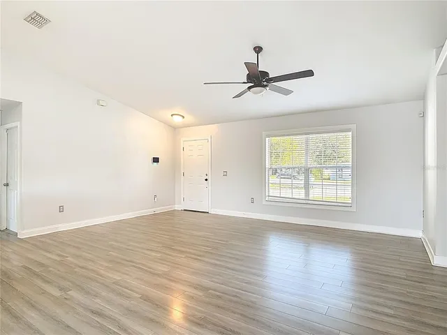 a view of an empty room and window with wooden floor