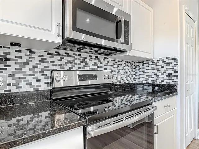 a kitchen with granite countertop a sink and white cabinets