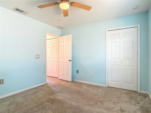 an empty room with a ceiling fan and carpet