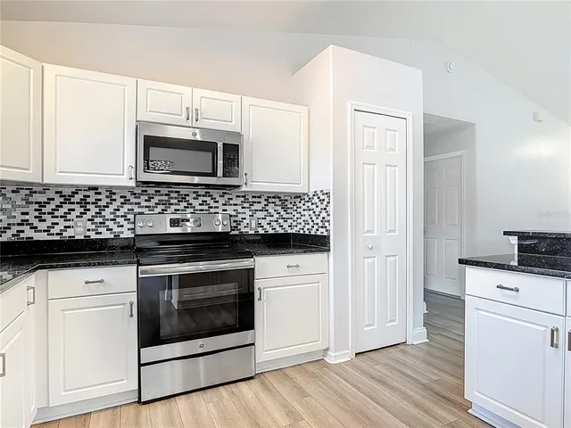 a kitchen with stainless steel appliances white cabinets and a stove a sink with wooden floor