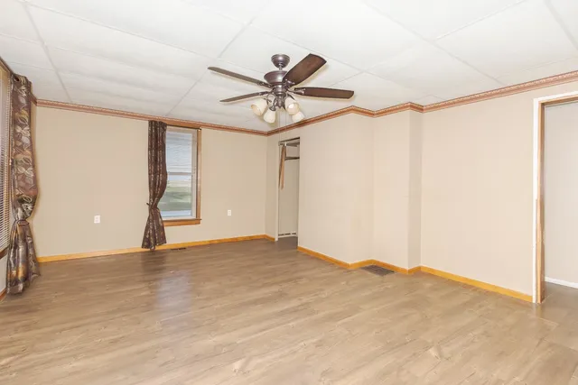 an empty room with windows and fan