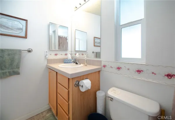 a bathroom with a sink mirror toilet and window