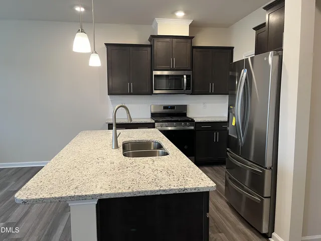 a kitchen with stainless steel appliances granite countertop a sink refrigerator and microwave