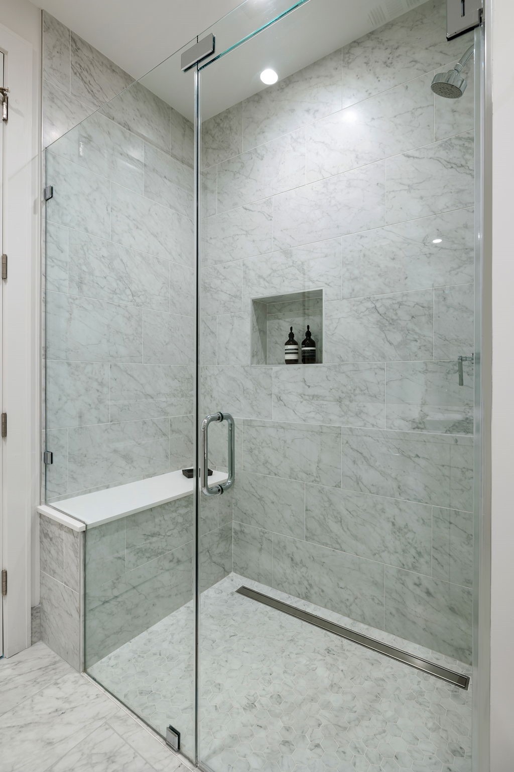 5656 San Felipe Street, Unit 1005 Houston, TX 77056 - Photo 11 of 33 Frameless glass shower features a full marble tile surround and built-in bench seating.