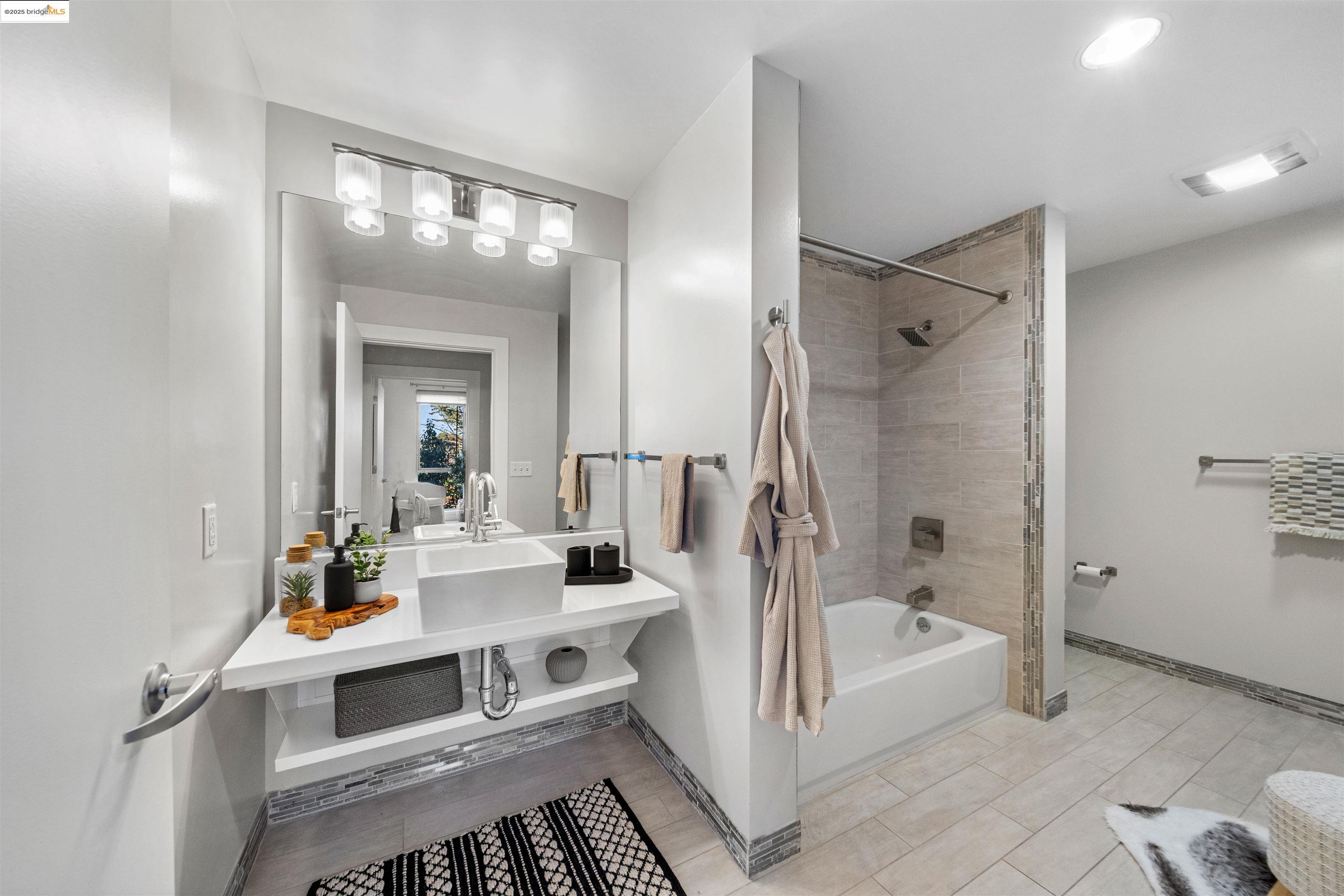 1201 Pine Street, Unit 363 Oakland, CA 94607 - Photo 12 of 25 a bathroom with a tub sink vanity and mirror