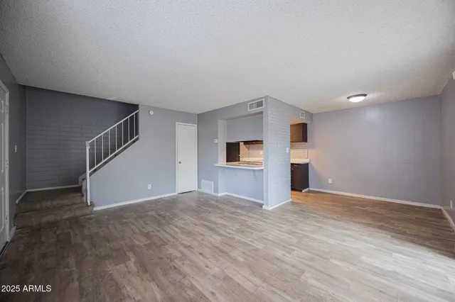 a view of an empty room with window and wooden floor