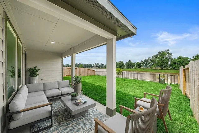 a view of a patio with couches potted plants and a big yard