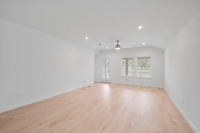 a view of an empty room with a window and wooden floor