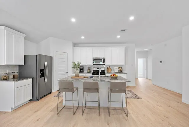 a kitchen with stainless steel appliances kitchen island granite countertop a refrigerator and a stove top oven