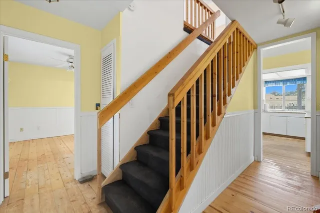 a view of staircase with lots of frames on wall and wooden floor
