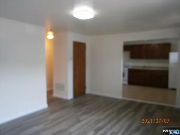 a view of an empty room with wooden floor and a fireplace