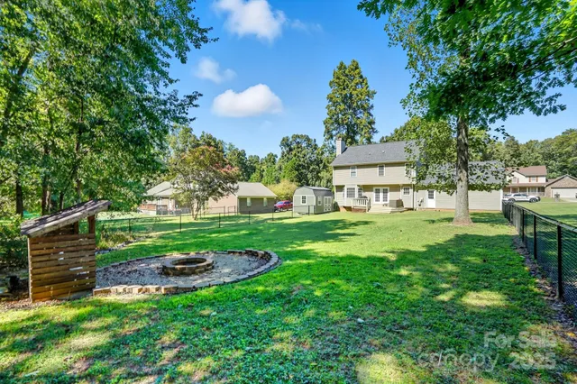a view of a backyard with table and chairs and potted plants and large trees