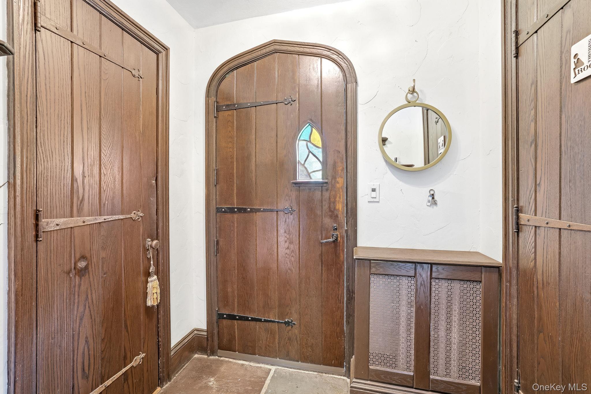 14 Overhill Road New Rochelle, NY 10804 - Photo 3 of 54 Arched wooden entry door with stained glass detail, complemented by dark wood paneling and stone tile flooring