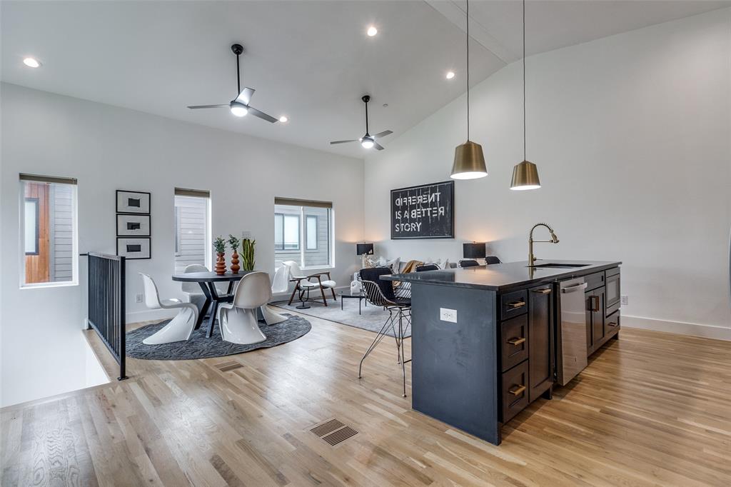 a open kitchen with stainless steel appliances granite countertop a refrigerator a sink dishwasher a stove and a dining table with wooden floor