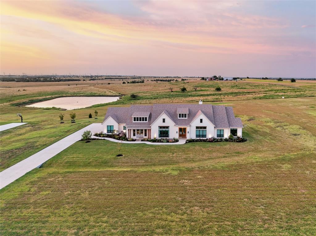 10932 Gregory Road Sanger, TX 76266 - Photo 40 of 40 Expansive property featuring a white exterior residence, a long paved driveway, a large pond, and a vast surrounding landscape