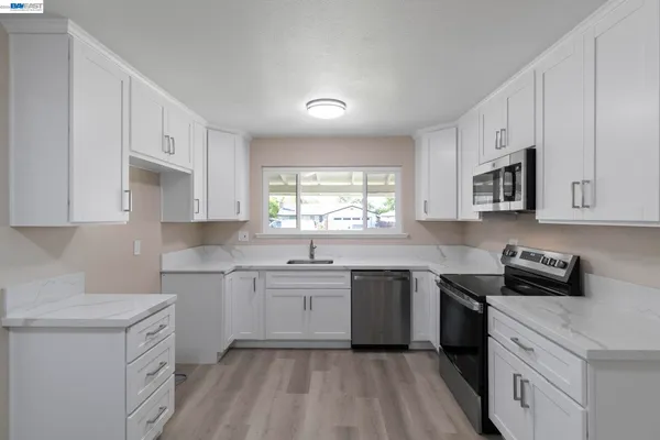 a kitchen with cabinets appliances a sink and a window